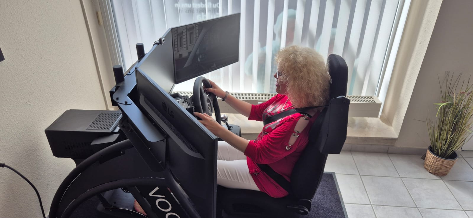 Eine Fahrschülerin sitzt konzentriert am professionellen Fahrsimulator mit mehreren Bildschirmen und Lenkrad in der Fahrschule Groß.